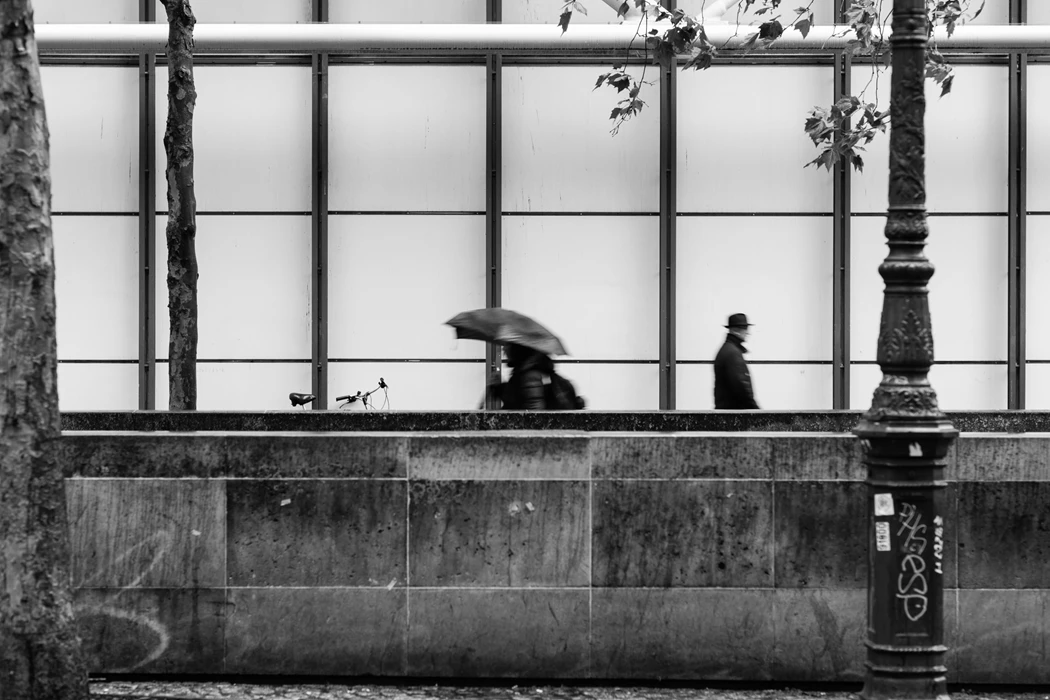 Black & white photo of a person sitting in a window with an umbrella
