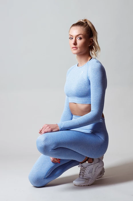 Studio lifestyle photo of a woman kneeling in gym clothing