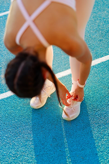 Colour photo of a person bending over to pick up a shoe