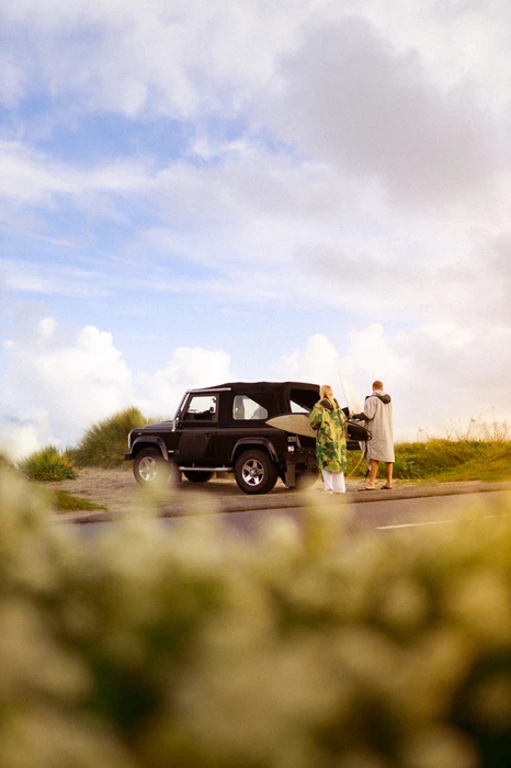 Colour photo of a man and woman standing next to a truck on a road