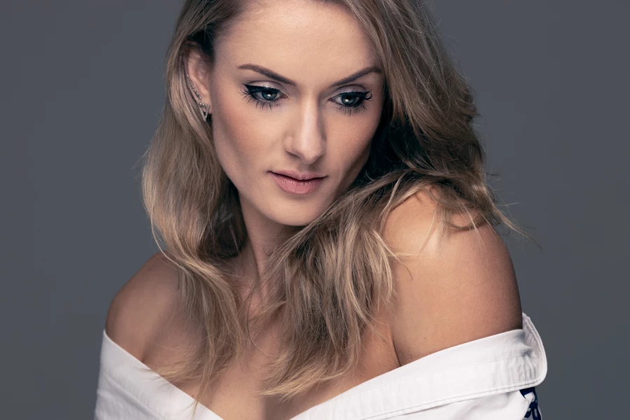 Studio beauty photo of woman in white shirt against grey background