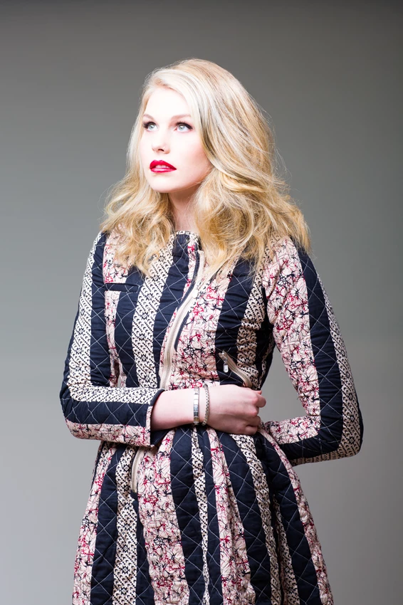 Studio fashion photo of woman in floral coat against grey background