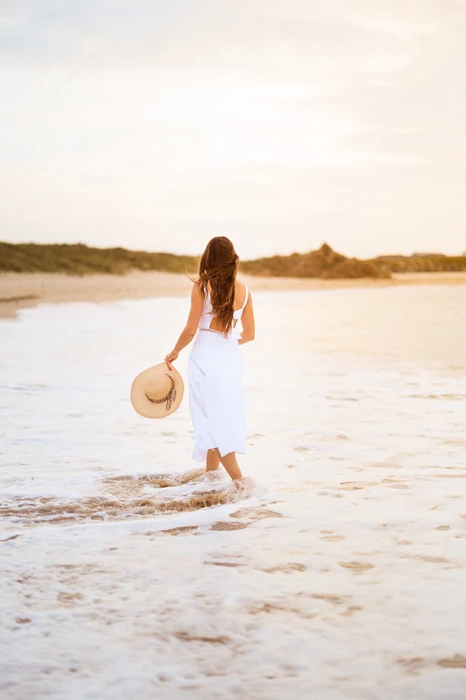 Colour photo of a person walking on a beach