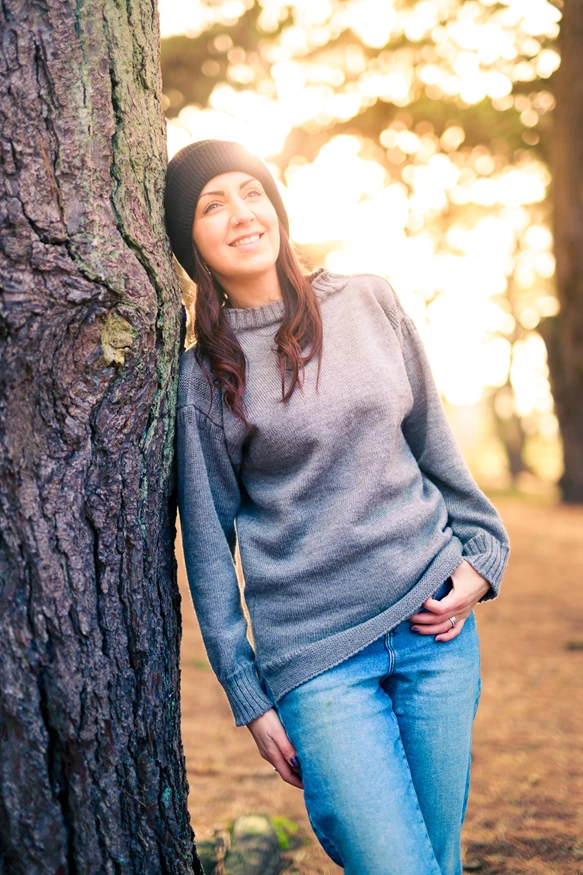 Colour photo of a woman standing next to a tree